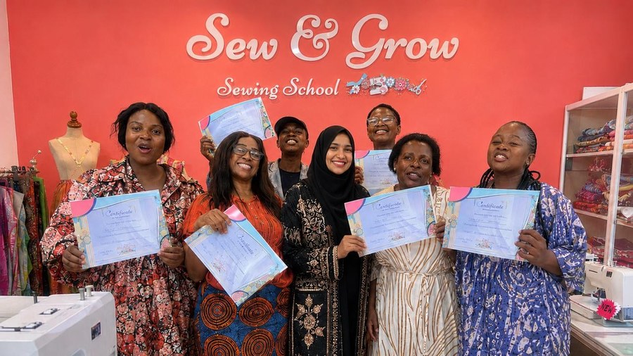 Proud graduates holding their certificates at Sew and Grow